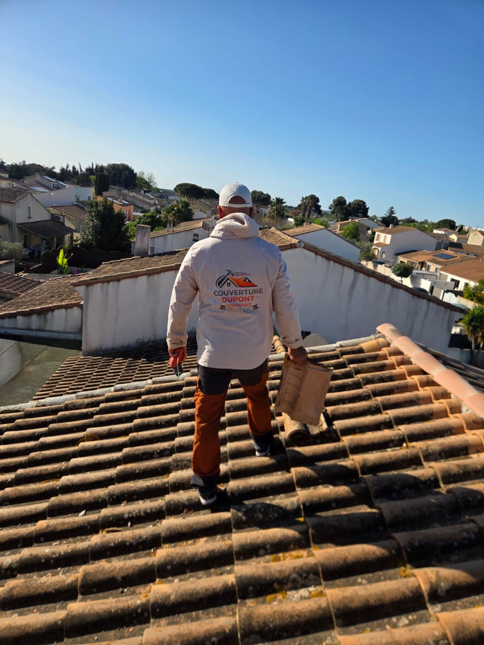 Couvreur Hortica Dupont sur une toiture à Lunel, sous un grand ciel bleu